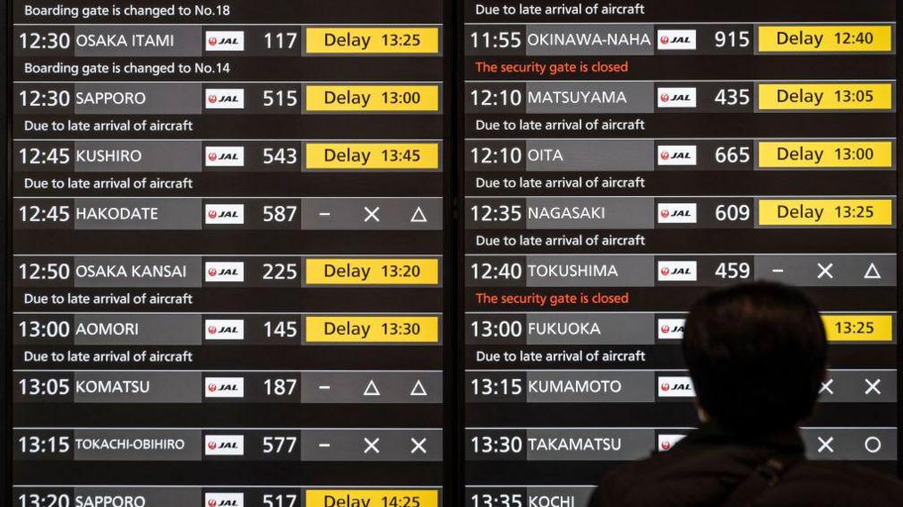 Një burrë shikon një ekran që tregon vonesën e fluturimeve të Japan Airlines në sallën e nisjeve të Aeroportit Haneda në Tokio më 26 dhjetor 2024. Japan Airlines më 26 dhjetor raportoi një sulm kibernetik që shkaktoi vonesa në fluturimet vendase dhe ndërkombëtare, por më vonë tha se e kishte gjetur dhe adresuar shkakun.