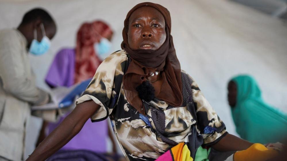 Halima Mohammed Adam, një paciente sudaneze me kolerë me një shall kafe mbi kokë dhe një fustan shumëngjyrësh, shikon ndërsa është ulur në një shtrat në një klinikë të improvizuar të drejtuar nga Kombet e Bashkuara në Tawila në Darfur, Sudan, më 5 gusht 2025.