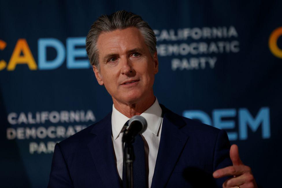 Gavin Newsom, i veshur me kostum blu dhe këmishë të bardhë, po flet në mikrofon në një podium përpara një posteri për Prop50, masën e tij të votimit për rindarjen e zonave zgjedhore, e cila u miratua nga votuesit këtë javë.