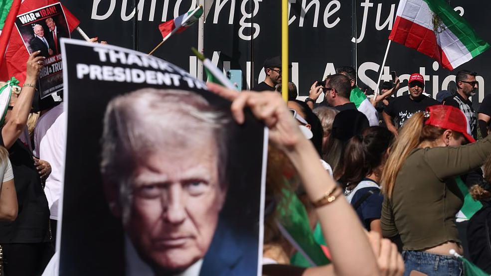 Njerëz që valëvisin flamuj dhe pankarta me imazhin e Trump në mbështetje të sulmit të tij ndaj Iranit