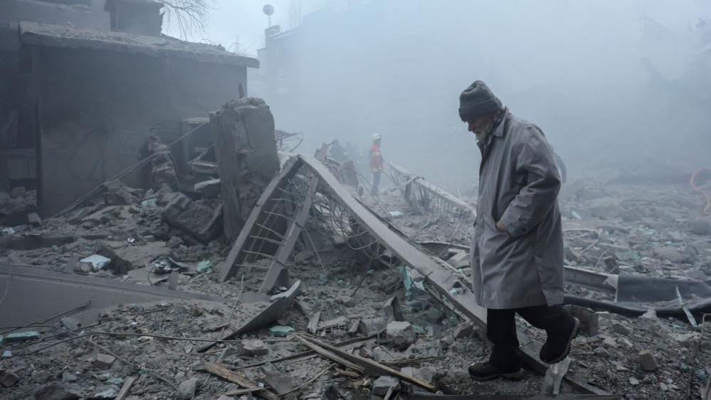 Një burrë ecën midis rrënojave pas një sulmi rus në një zonë banimi në qytetin e Kharkiv, në verilindje të Ukrainës. Foto: 2 janar 2026