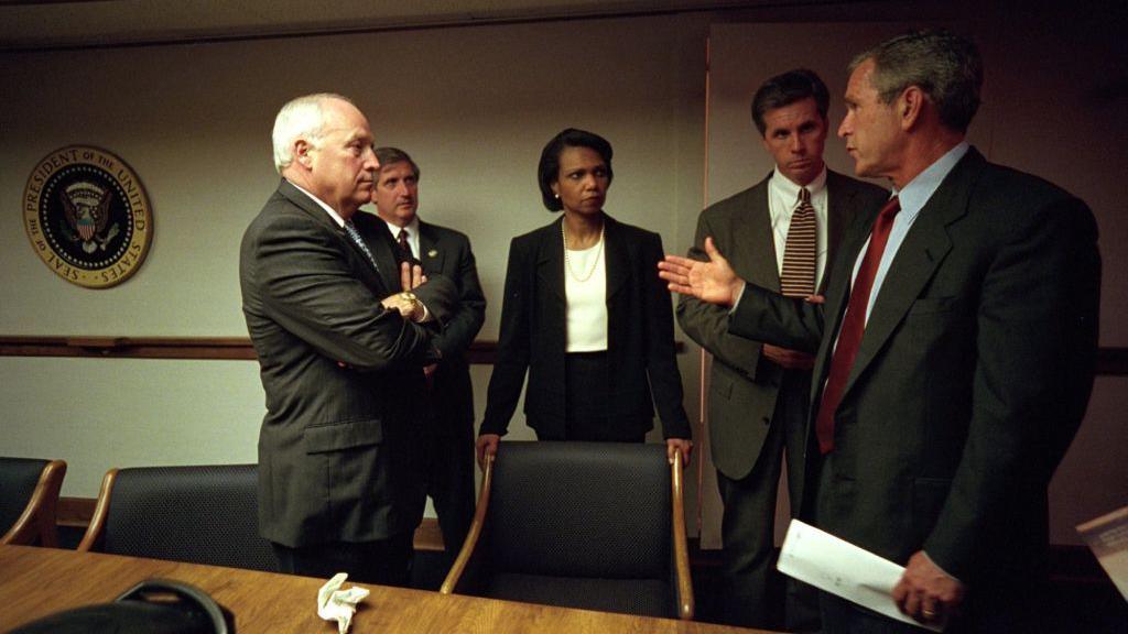 Cheney, Condoleezza Rice dhe George W Bush, si dhe dy burra të tjerë, duke folur në një sallë mbledhjesh