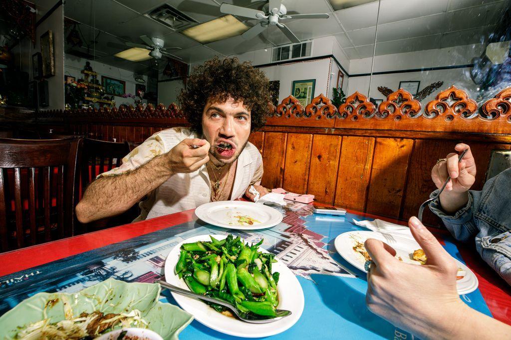 Benny Blanco i ulur në një restorant duke futur një lugë ushqim në gojë. Një pjatë me perime është në tavolinë përpara tij.