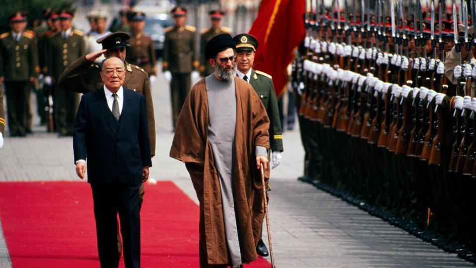 Presidenti kinez Yang Shangkun (1907 - 1998) (në qendër majtas) dhe Presidenti iranian Ali Khamenei (në qendër djathtas) ecin së bashku gjatë një ceremonie mirëseardhjeje për vizitën shtetërore të këtij të fundit, Pekin, Kinë, 11 maj 1989.