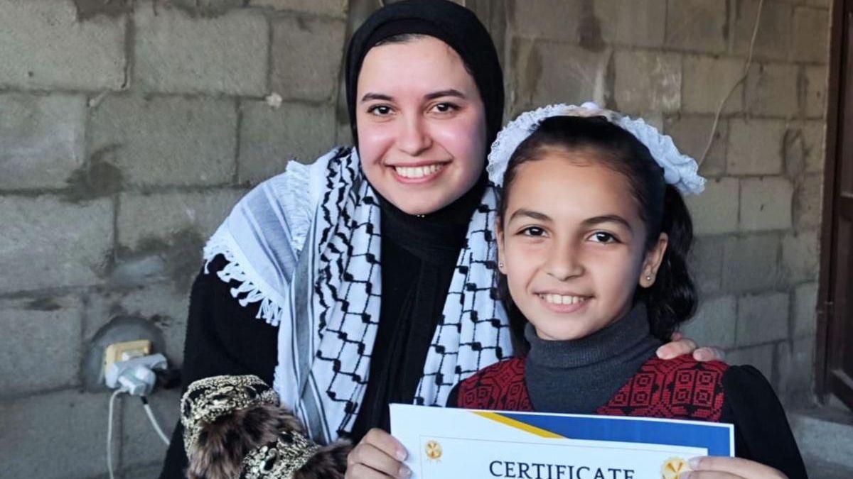 Sana el-Azab me një student, i cili mban lart një certifikatë arritjeje, në Gazën qendrore
