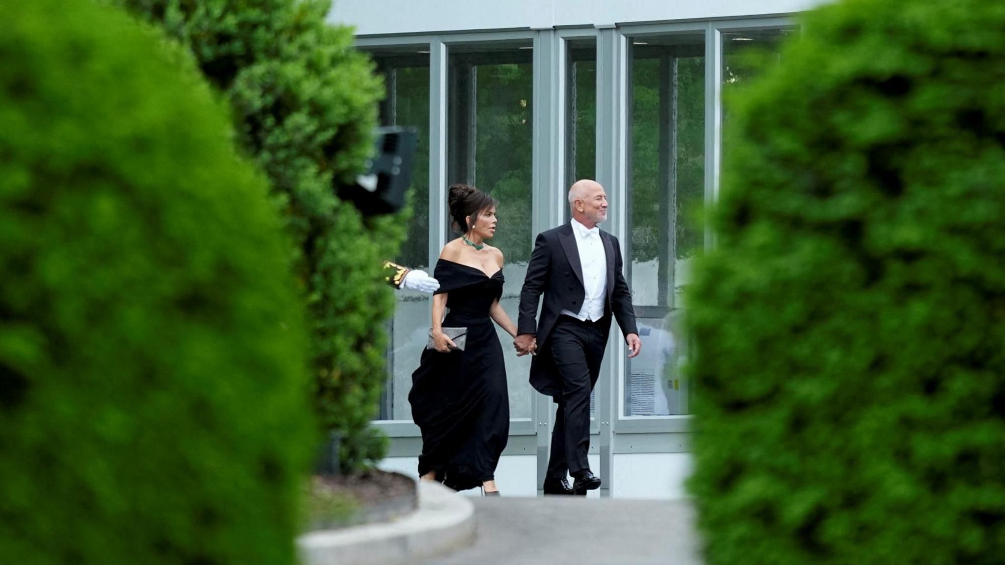 Jeff Bezos shihet duke ecur jashtë Shtëpisë së Bardhë me gruan e tij Lauren Sanchez. Të dy janë të veshur me kravatë të zezë.