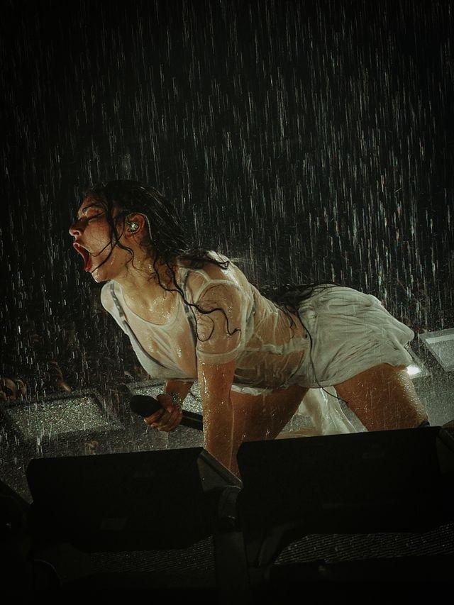 Charli XCX me një veshje të bardhë e të shkurtër, në të katër këmbët, duke u lagur me ujë në skenë