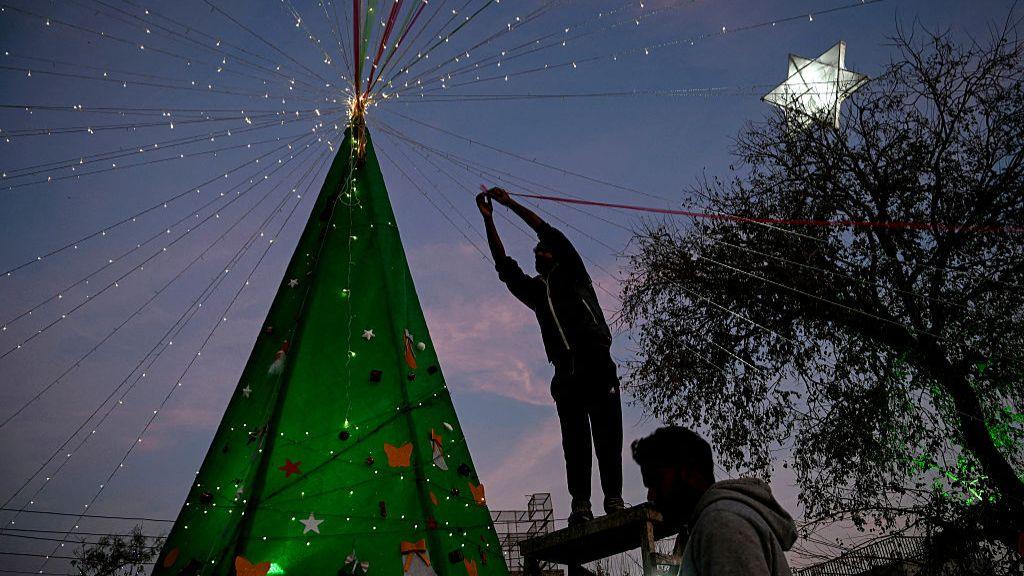 Një burrë dekoron një pemë të Krishtlindjeve gjatë festimeve të pragut të Krishtlindjeve në Islamabad, Pakistan, më 24 dhjetor 2025.
