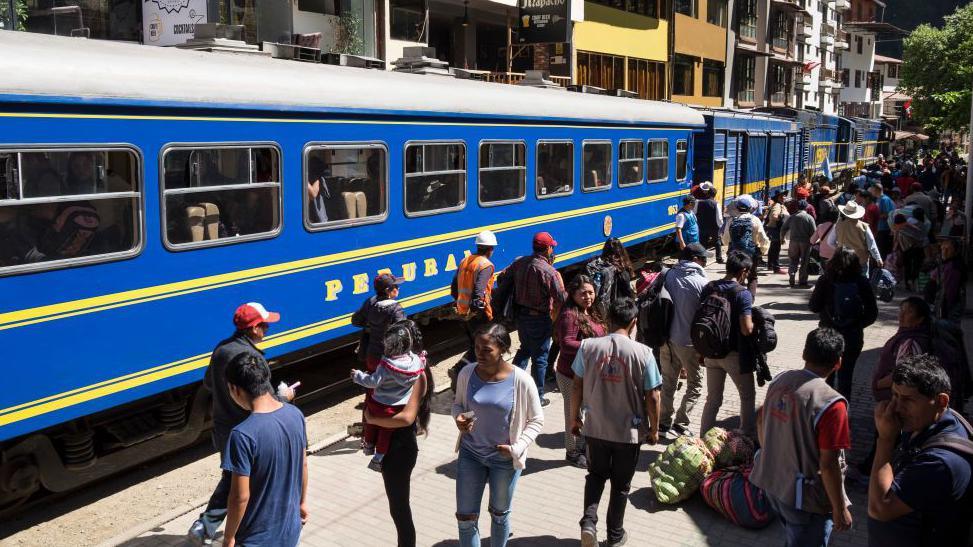 Një tren në stacionin në Aguas Calientes, me njerëz që qëndrojnë në platformë