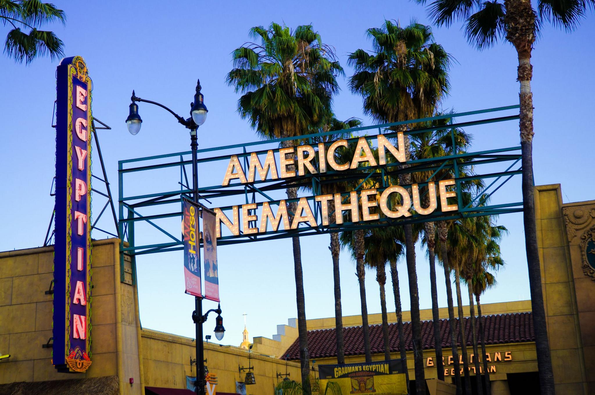 Një vështrim në pjesën e jashtme të Teatrit Egjiptian në Los Angeles. Emri i tij është i ndriçuar me drita në tendë dhe një tjetër tabelë neoni shkruan "American Cinematheque"