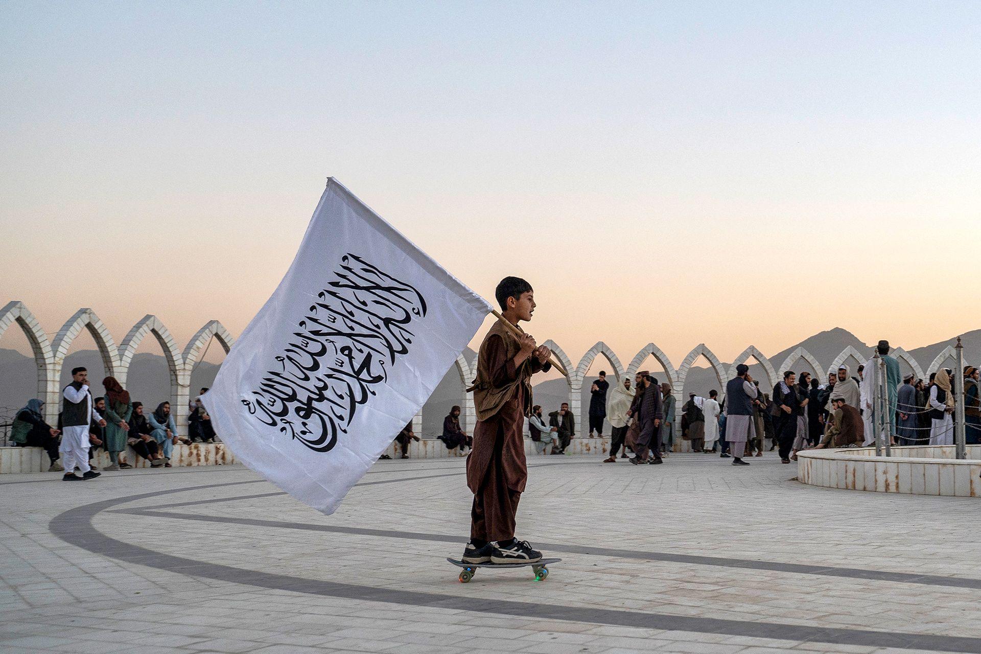 Një djalë afgan mban flamurin e talebanëve ndërsa ngjitet me patinazh në majën e kodrës Wazir Akbar Khan në Kabul më 13 tetor 2025.