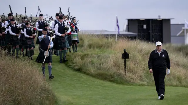 Donald Trump ndiqet nga gajdexhinj ndërsa ai ecën në fushën e tij skoceze të golfit në Aberdeenshire.
