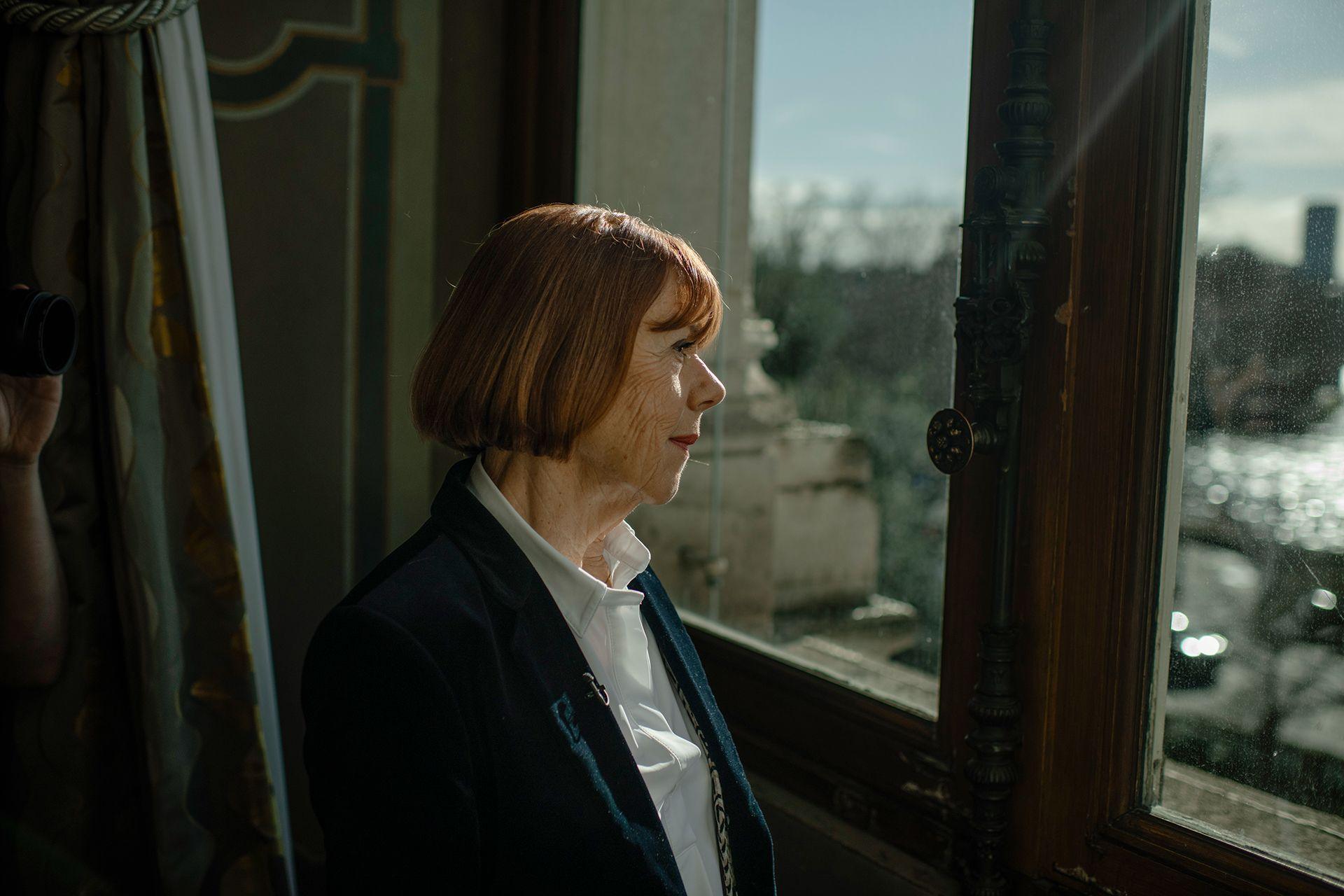 Gisèle Pelicot, me këmishë të bardhë dhe xhaketë të zezë, shikon nga dritarja e Hôtel de Ville në Paris, Francë.