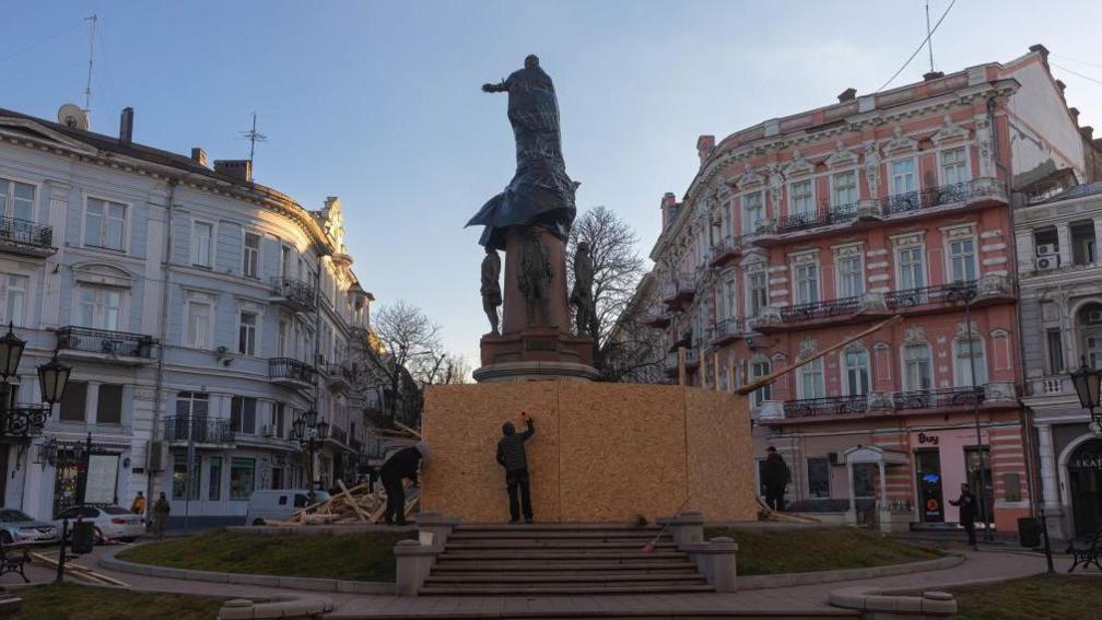 Një statujë e madhe në mes të një sheshi çmontohet