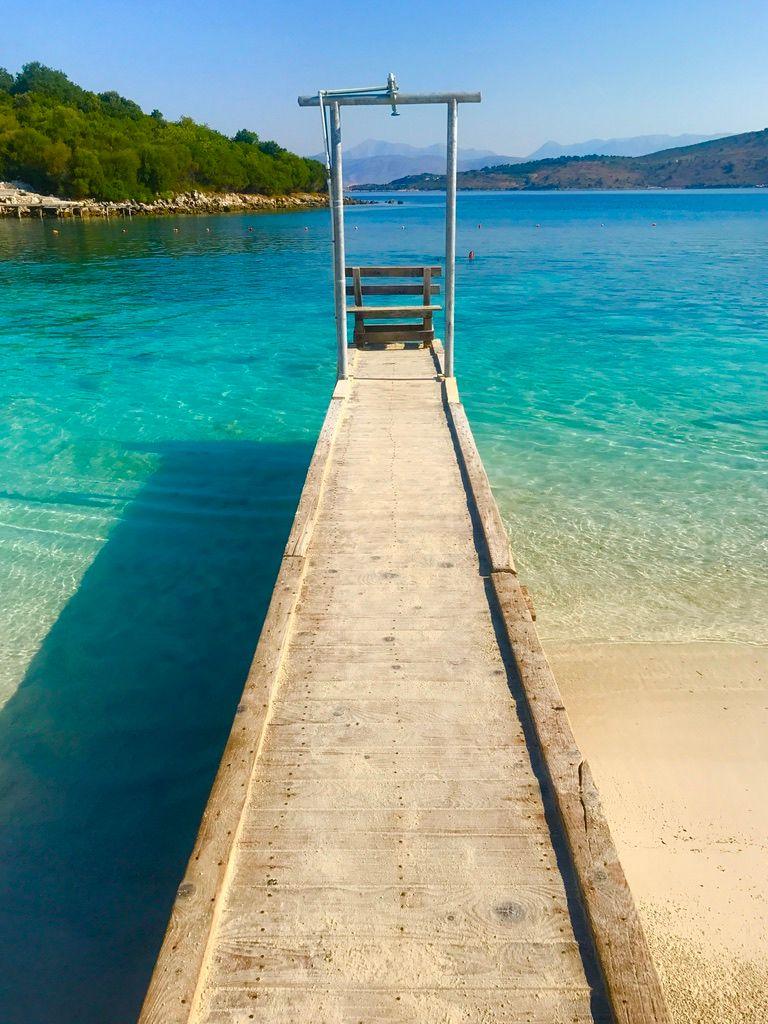 Një skelë e vogël në plazh në Shqipëri. Uji është një blu e shkëlqyer.