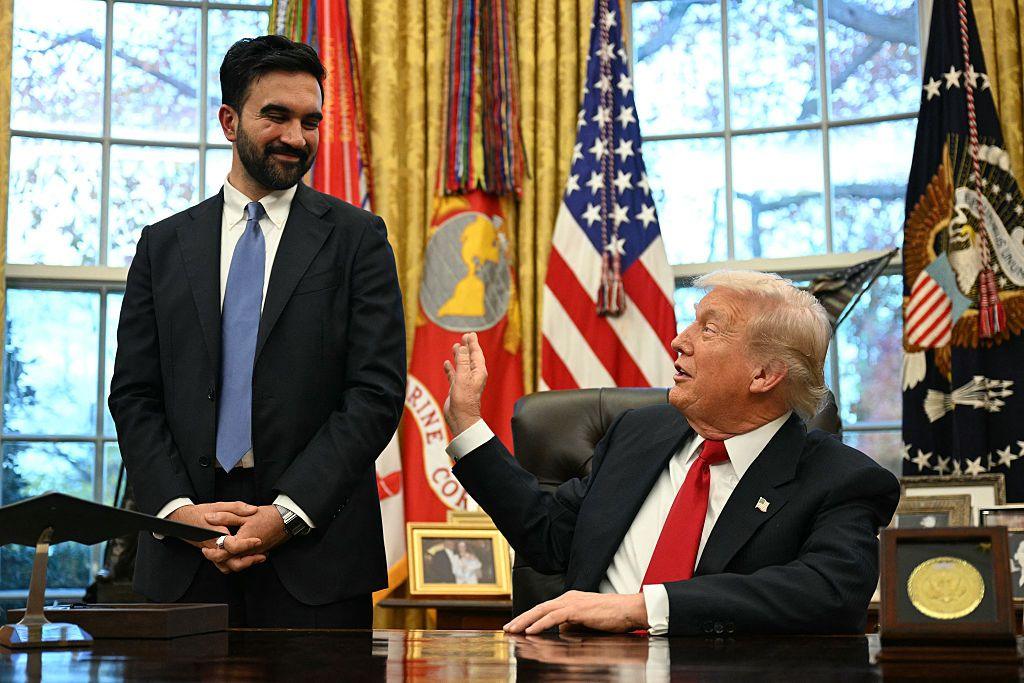 Mamdani shihet duke qëndruar pranë Trump, i cili është ulur pas tavolinës së tij në Zyrën Ovale. Të dy po buzëqeshin dhe Trump po i zgjatet dorën për ta prekur me shaka në krah.