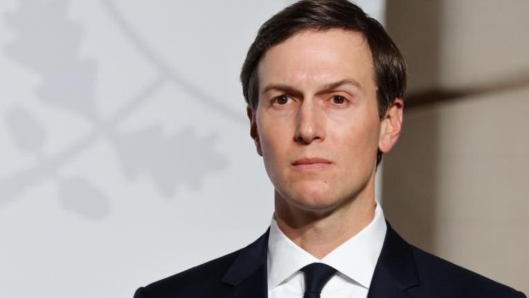 Një imazh i Jared Kushnerit të veshur me një kostum të zi me një këmishë të bardhë që shikon në distancë.