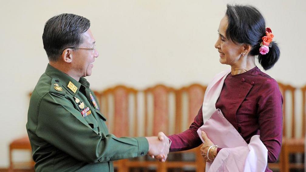 Gjenerali i Lartë Min Aung Hlaing, Komandanti i Përgjithshëm i Myanmarit (majtas) dhe udhëheqësja e partisë së Lidhjes Kombëtare për Demokraci (NLD), Aung San Suu Kyi (djathtas), shtrëngojnë duart pas takimit të tyre në zyrën e Komandantit të Përgjithshëm në Naypyidaw më 2 dhjetor 2015.