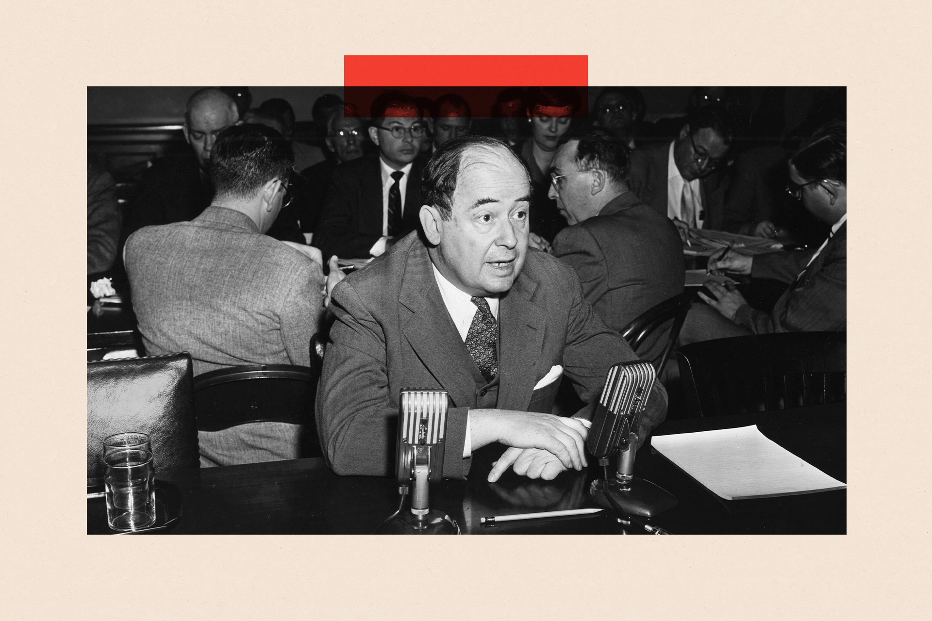Imazh bardh e zi i John von Neumann i veshur me kostum dhe i ulur në një tavolinë