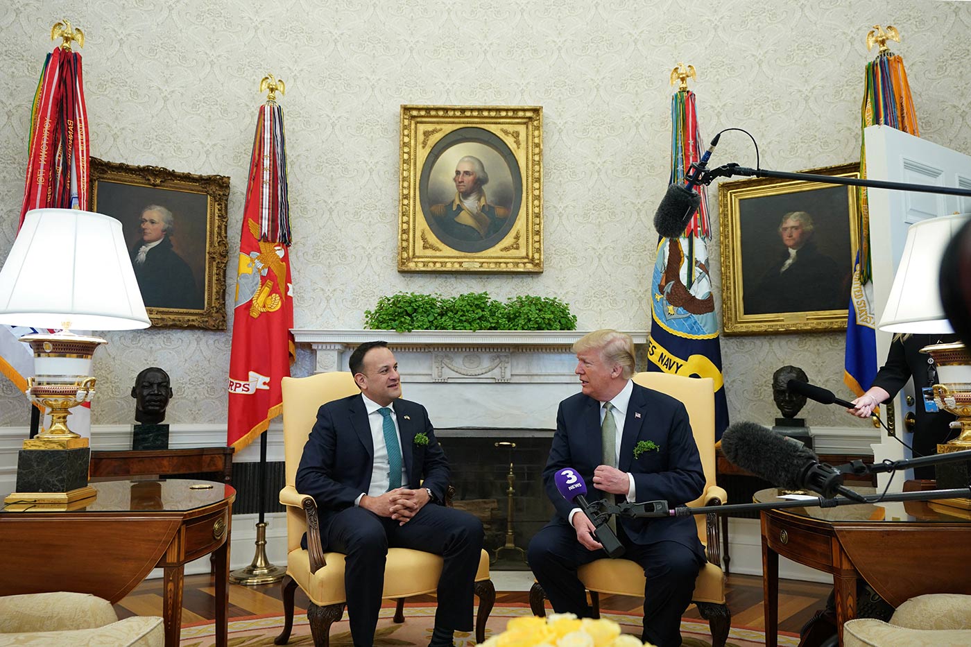 Donald Trump takohet me kryeministrin e Irlandës Leo Varadkar në Zyrën Ovale në kolltuqe të verdha përpara një oxhaku të bardhë. Dhoma ka mure me motive ngjyrë kremi të zbukuruara me tre portrete të figurave historike të kornizuara dhe të rrethuara nga flamuj të lartë ushtarakë mbi mbështetëse ari. Një bimë e gjelbër qëndron mbi oxhak, dhe dy llamba të mëdha të bardha mbi tavolina anësore prej druri ofrojnë ndriçim të butë.